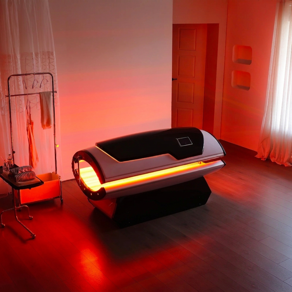 Full-body LED light therapy capsule glowing with warm red light in a treatment room